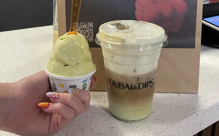 Pistachio gelato in Houston, a scoop held up at our counter beside a layered latte in a Dubai & Dips cup