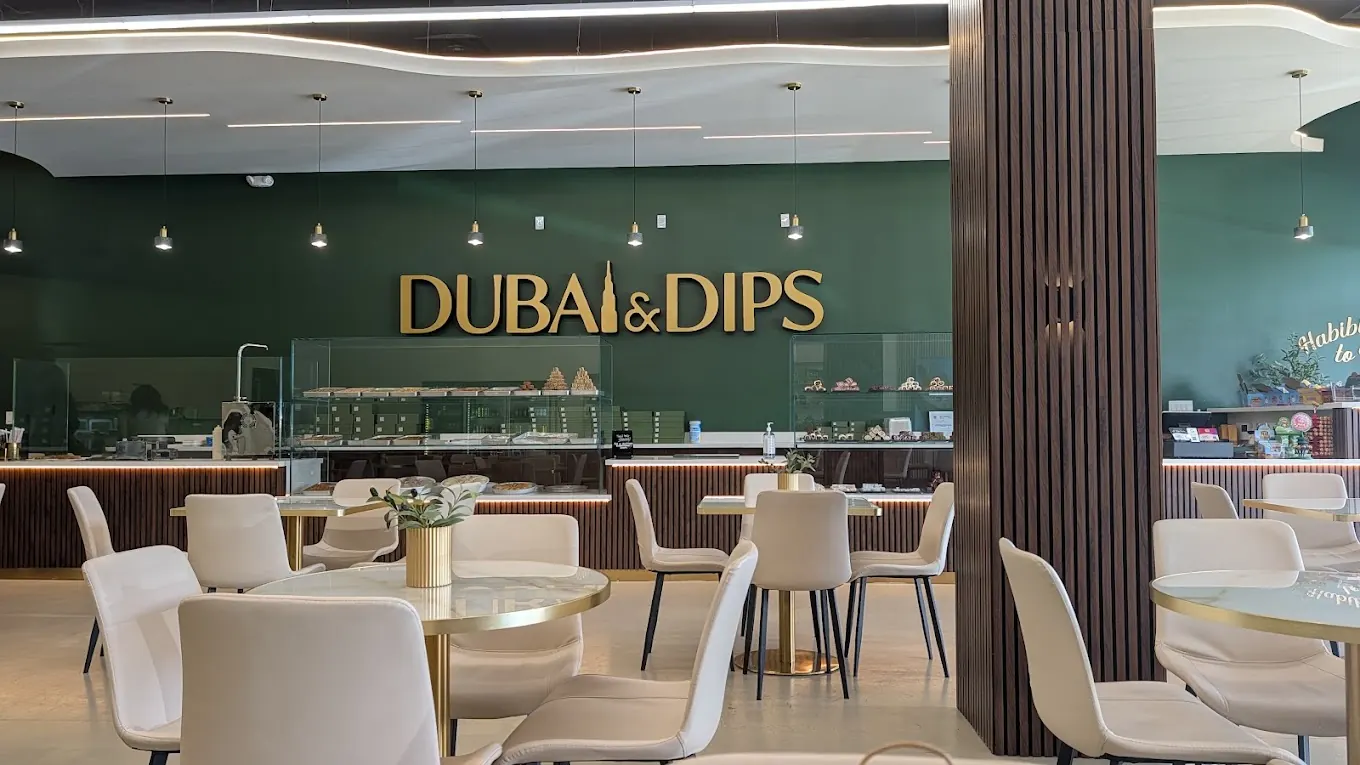 Late night dessert in Houston at Dubai & Dips, with the gold sign on the green wall over the pastry counter and marble tables